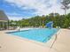 Community pool features a slide, lounge seating, tables with umbrellas, and is surrounded by mature trees at 514 Bonville Ct, Fuquay Varina, NC 27526