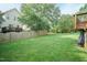 Spacious backyard featuring a wooden fence, lush greenery, and a small wooden deck at 5501 Southern Cross Ave, Raleigh, NC 27606