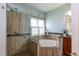 A beautifully tiled bathroom features a glass enclosed shower and corner jacuzzi tub with natural light at 5501 Southern Cross Ave, Raleigh, NC 27606