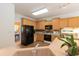 Kitchen with wood cabinets, black appliances, and a view into an adjacent dining area at 5501 Southern Cross Ave, Raleigh, NC 27606