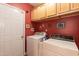 Laundry room with a white washer and dryer, red walls, and ample overhead cabinet space at 5501 Southern Cross Ave, Raleigh, NC 27606