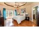 Main bedroom with a tray ceiling, a ceiling fan, hardwood flooring, and lots of natural light at 5501 Southern Cross Ave, Raleigh, NC 27606