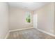 A bright bedroom features a window, a door, neutral carpet, and freshly painted walls at 59 White Quartz Pl, Fuquay Varina, NC 27526