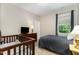 A bedroom featuring a crib and a bed, illuminated by a window and a bedside lamp at 59 White Quartz Pl, Fuquay Varina, NC 27526