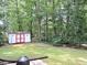 Backyard with shed, set against a backdrop of mature trees, offering plenty of privacy and storage space at 8 Woodsprite Ct, Durham, NC 27703