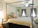 Bedroom with decorative pillows and four-poster bed with natural lighting through windows at 8 Woodsprite Ct, Durham, NC 27703