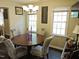Cozy dining area with a chandelier, a round table with four chairs, and natural light from two windows at 8 Woodsprite Ct, Durham, NC 27703