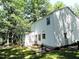 Back exterior view of the home, set against a wooded backdrop and featuring a back patio at 8 Woodsprite Ct, Durham, NC 27703