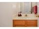 This is a bathroom with a wooden cabinet beneath a light colored countertop with a sink, mirror, and wall mounted towel rack at 809 Maple Shade Ln, Apex, NC 27502