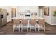 Kitchen island with quartz countertop and four bar stools surrounded by white cabinetry and stainless steel appliances at 817 Ottawa Dr, Garner, NC 27529