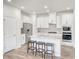 Bright kitchen features white cabinets, stainless steel appliances, an island with stools, and wood flooring at 825 Ottawa Dr, Garner, NC 27529