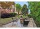 Landscaped backyard boasts a stone firepit and seating surrounded by mature trees at 1008 Justice Walk Ave, Morrisville, NC 27560