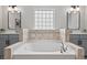 Bright bathroom featuring a large soaking tub with tile surround and dual gray vanity sinks at 1008 Justice Walk Ave, Morrisville, NC 27560
