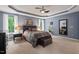 Main bedroom features a tray ceiling, plush carpet, two windows, and a ceiling fan at 1008 Justice Walk Ave, Morrisville, NC 27560