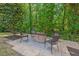 Outdoor patio area with a stone firepit and comfortable seating surrounded by trees at 1008 Justice Walk Ave, Morrisville, NC 27560