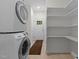 Bright laundry room with storage shelves, stacked washer/dryer, and entry to the back yard at 1027 Holden Rd, Youngsville, NC 27596