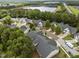 An aerial view highlights a neighborhood near a lake, surrounded by lush green trees and well-kept townhomes at 10404 Dapping Dr, Raleigh, NC 27614