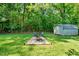 This backyard features a fire pit area, shed, lawn, and surrounding trees at 105 Choyce Ct, Garner, NC 27529