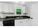 Bright kitchen featuring white cabinets, granite countertops, stainless steel sink, and view to outdoor greenery at 105 Choyce Ct, Garner, NC 27529