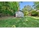 A backyard shed sits on a lush green lawn surrounded by trees and a chain-link fence at 105 Choyce Ct, Garner, NC 27529