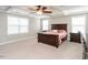 Main bedroom featuring a tray ceiling, fan, carpet, and ample natural light at 105 Pink Dogwood Ln, Mebane, NC 27302