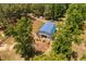 Aerial view of horse barn featuring blue roof and horses gathered in front. Surrounded by lush trees and green fields at 108 Cedarwood Dr, Louisburg, NC 27549