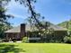 Back exterior showing a covered patio, brick chimney, and manicured lawn with flowerbeds at 108 Cedarwood Dr, Louisburg, NC 27549
