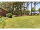 Lawn beside a brick house with a barn in the background surrounded by trees at 108 Cedarwood Dr, Louisburg, NC 27549