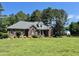 Charming brick home, well-manicured lawn, mature trees, and architectural details on a clear, sunny day at 108 Cedarwood Dr, Louisburg, NC 27549