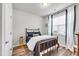 Comfortable bedroom featuring a window with blinds and curtains, a wooden bed frame, and wood floors at 1096 Aberlour Ln, Burlington, NC 27215