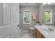 Well-lit bathroom featuring a shower-tub combo, modern vanity, and window offering backyard views at 110 Fairchild Downs Pl, Cary, NC 27518