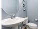 Stylish powder room featuring a pedestal sink, round mirror, and decorative wall art at 1101 Hazelmist Dr, Youngsville, NC 27596