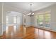 Elegant dining room with hardwood floors, chandelier, and large windows creating a bright and inviting atmosphere at 117 Arborhill Ln, Holly Springs, NC 27540