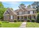 Charming two-story brick home boasts a well-manicured lawn and inviting covered front porch with stately white columns at 117 Arborhill Ln, Holly Springs, NC 27540