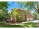Brick home featuring an attached two-car garage, fenced yard, and outdoor deck surrounded by mature trees at 117 Arborhill Ln, Holly Springs, NC 27540