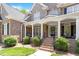 Inviting front porch features brick stairs, white columns, iron railings, and tasteful landscaping around the property at 117 Arborhill Ln, Holly Springs, NC 27540