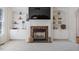 Living room with a fireplace, built-in shelving, ceiling fan, and large windows, offering a comfortable and stylish gathering space at 117 Arborhill Ln, Holly Springs, NC 27540