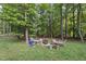 Landscaped backyard with a fire pit, surrounded by mature trees and seating area at 1211 New Grissom Way, Wake Forest, NC 27587