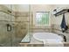 Bright bathroom featuring a glass enclosed shower and soaking tub with decorative window at 1211 New Grissom Way, Wake Forest, NC 27587