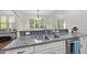 Kitchen featuring a stainless steel sink, gray granite countertops, and white cabinets at 1211 New Grissom Way, Wake Forest, NC 27587