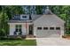 Inviting front exterior featuring a charming porch, stone accents, and a classic two-car garage at 136 Hatchet Cv, Louisburg, NC 27549