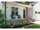 Cozy front porch with a charming seating area, stone accents, and a well-lit entrance at 136 Hatchet Cv, Louisburg, NC 27549