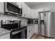 Close-up of the white kitchen featuring stainless steel appliances and granite countertops at 136 Hatchet Cv, Louisburg, NC 27549