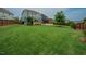 Expansive backyard featuring a well-maintained lawn, a wooden fence, a covered patio and manicured landscaping at 2020 Cotton Barn Ct, Wendell, NC 27591