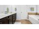 Well-lit bathroom features double vanity with dark cabinets, tile floor and a soaking tub at 213 Florence Dr, Clayton, NC 27527