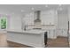 Bright kitchen showcasing a large island, white cabinets, stainless steel appliances, and hardwood floors at 248 Ashford Dr, Pittsboro, NC 27312
