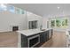 Island with sink, stainless appliances, and open floorplan with fireplace and large windows at 248 Ashford Dr, Pittsboro, NC 27312