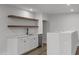 Kitchenette features white cabinets, marble countertops, stainless steel dishwasher, and wooden floating shelves at 248 Ashford Dr, Pittsboro, NC 27312