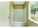 A clean bathroom featuring a combined shower and bathtub and a window with a view of the outdoor landscape at 2832 Ladale Ln, Mebane, NC 27302