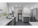 Well-lit kitchen with stainless steel appliances, gray lower cabinets, and laundry room access at 3 Haggis Ct, Durham, NC 27705